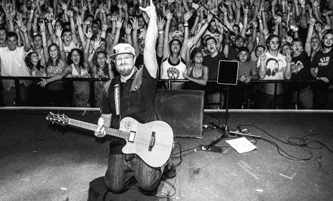 Brett Wilson rocking on stage in front of cheering fans.